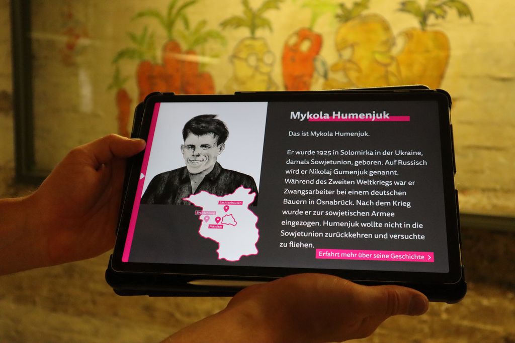 Ein Nutzer hält ein Tablet mit der Lern-App in den Händen. Auf dem Screen ist ein Porträtbild mit Text.
